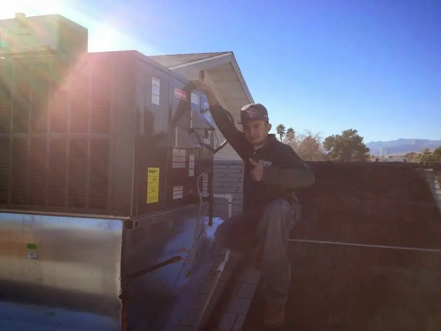 HVAC technician performing AC Tune-Up on a rooftop unit in Piqua