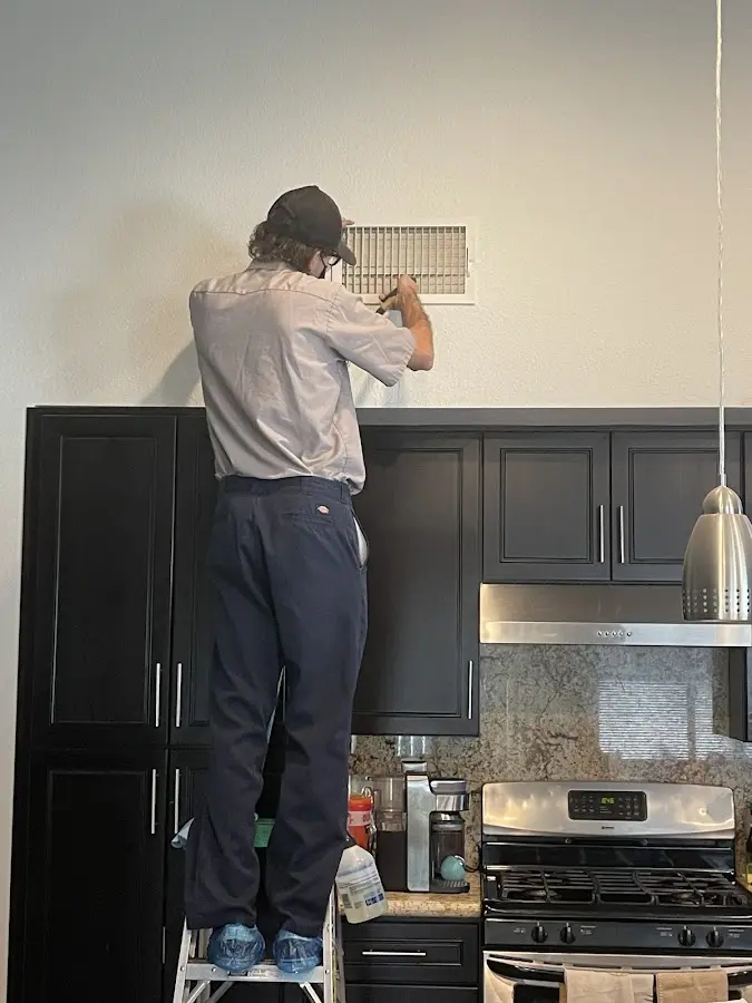 Technician inspecting an air vent during HVAC service in Piqua